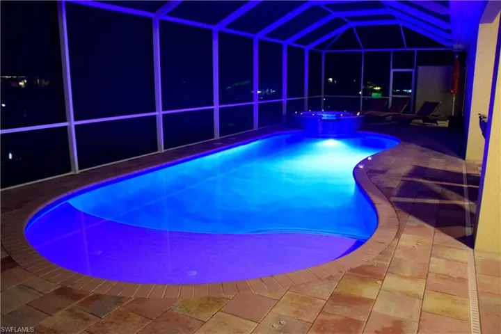 View of swimming pool featuring a lanai, a patio area, and an in ground hot tub