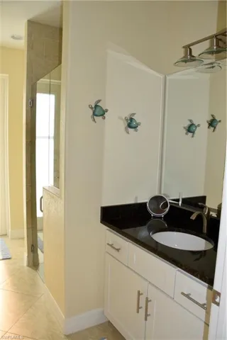 Bathroom with tile patterned flooring, vanity, and a shower with door