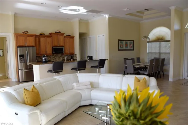 Living room with light parquet flooring, a towering ceiling, and ornamental molding
