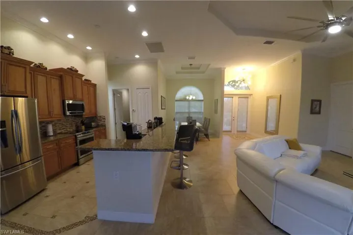 Kitchen featuring appliances with stainless steel finishes, a kitchen island, ornamental molding, and a kitchen breakfast bar