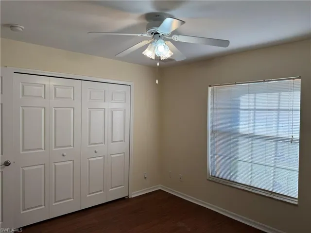 Unfurnished bedroom featuring dark wood-style flooring, ceiling fan, and a closet
