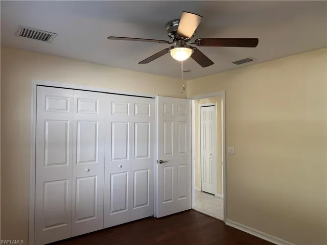 Unfurnished bedroom with dark wood-style flooring, ceiling fan, and a closet