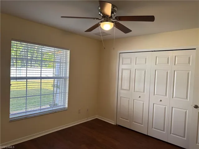 Unfurnished bedroom featuring ceiling fan, dark wood-style flooring, and a closet