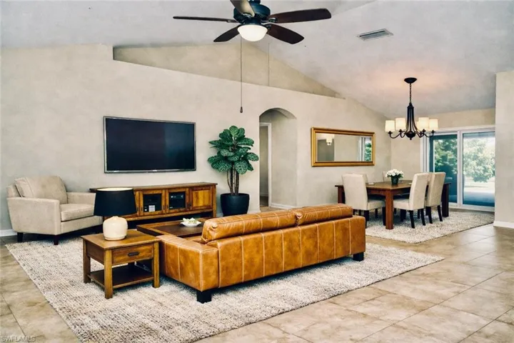 Living area with lofted ceiling, ceiling fan, arched walkways, and a chandelier