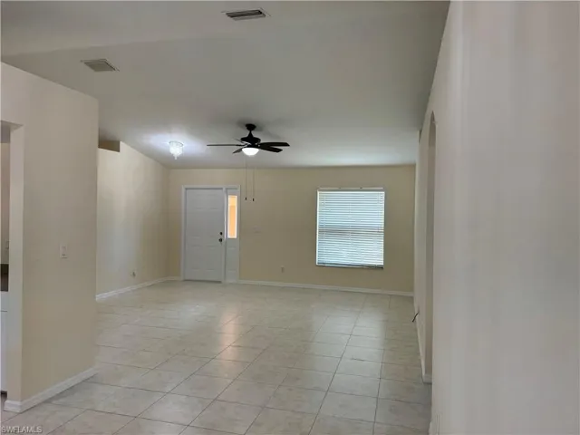 Empty room with ceiling fan, light tile patterned floors, and arched walkways