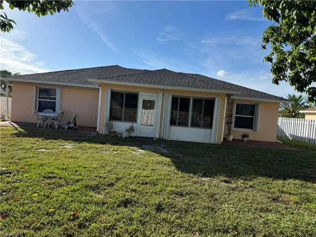 Back of house with stucco siding and roof with shingles