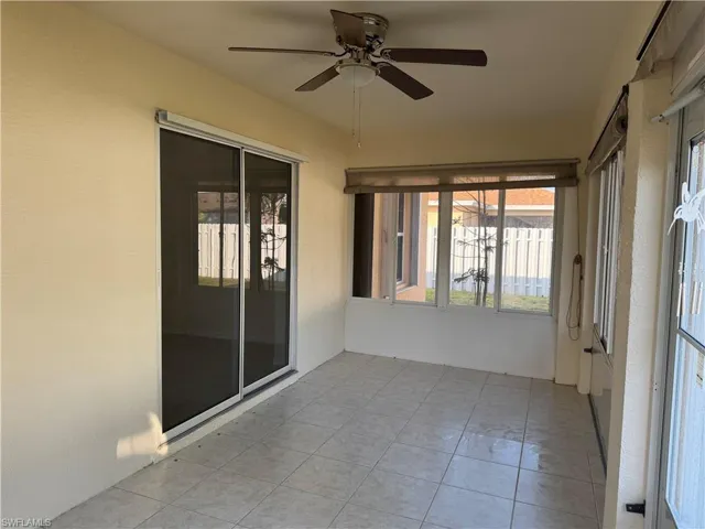 Unfurnished sunroom with a ceiling fan and tile patterned flooring