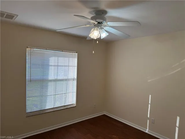 Spare room featuring dark wood-style flooring and a ceiling fan
