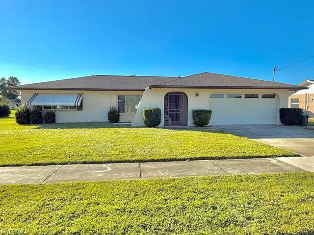 Ranch-style house with driveway, stucco siding, an attached garage, and a front lawn