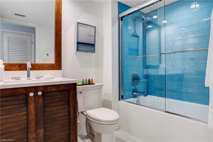 Full bathroom featuring shower / bath combination with glass door, tile patterned floors, vanity, and toilet