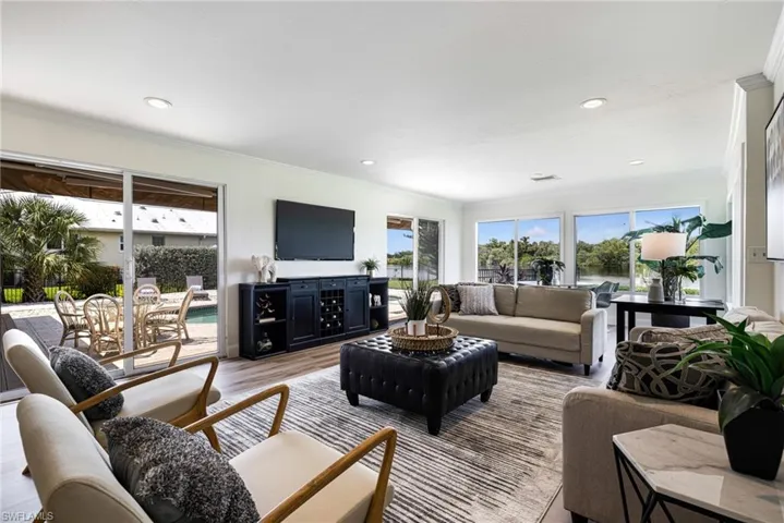 Living area with ornamental molding, wood finished floors, plenty of natural light, and recessed lighting