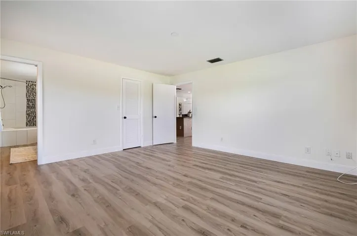 Unfurnished bedroom with light wood-type flooring and connected bathroom