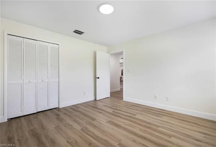 Unfurnished bedroom featuring wood finished floors and a closet