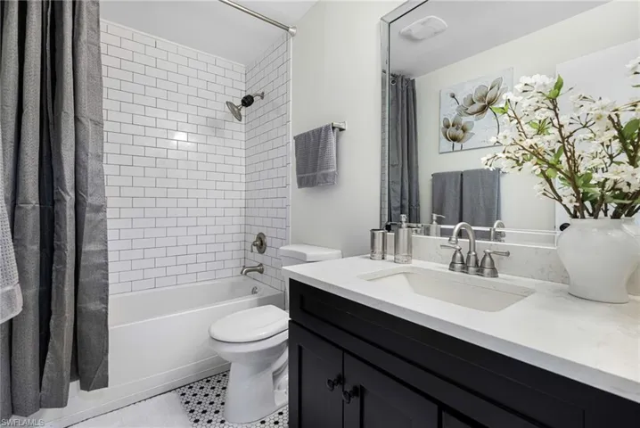 Full bathroom featuring shower / bath combo with shower curtain, vanity, and light tile patterned flooring