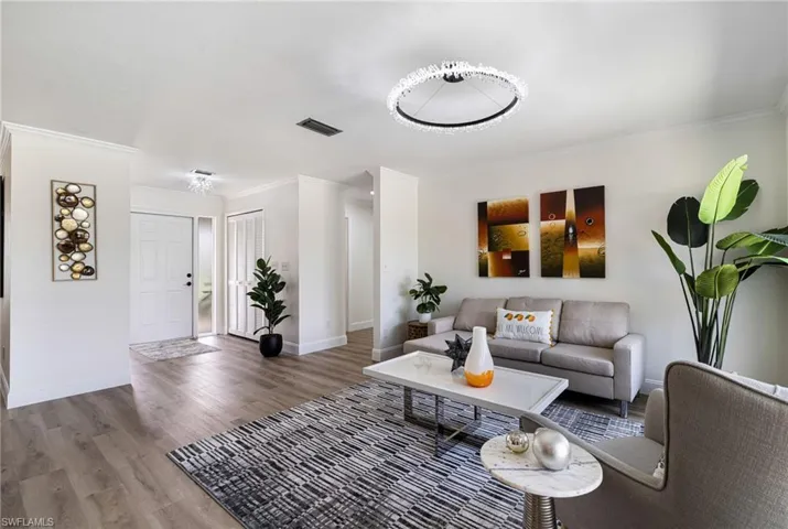 Living room with ornamental molding, wood finished floors, and a chandelier