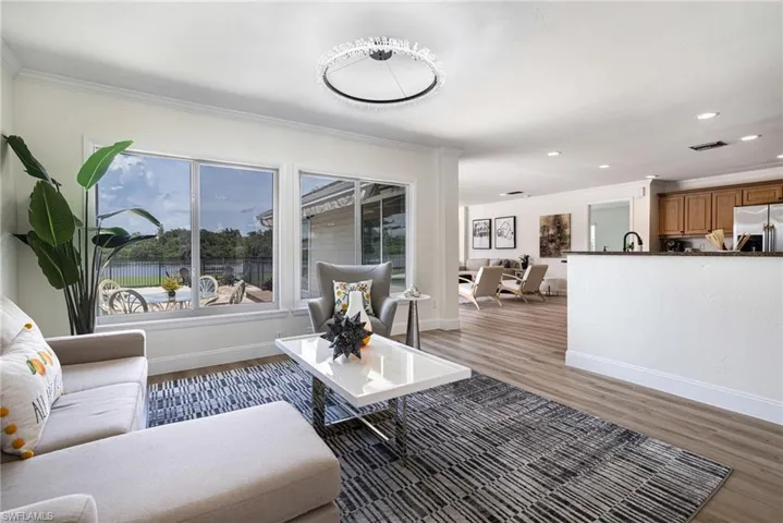 Living room featuring light wood-type flooring, recessed lighting, ornamental molding, and a water view