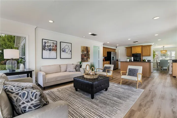 Living area with ornamental molding, light wood-style floors, and recessed lighting