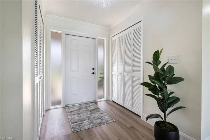 Foyer entrance with crown molding and wood finished floors