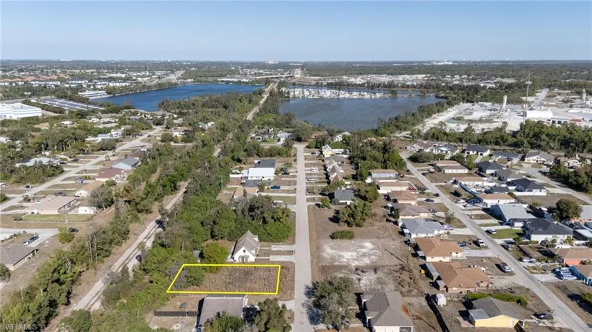 Aerial perspective of suburban area with property boundaries highlighted, a large body of water, and a notable bridge