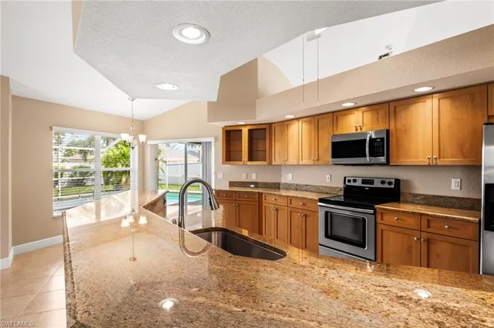 Kitchen featuring brown cabinets, lofted ceiling, a sink, and stainless steel appliances