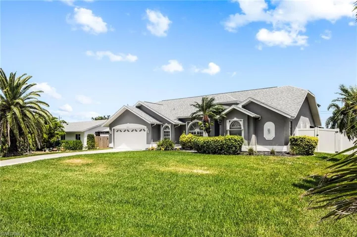 View of front of house featuring concrete driveway, stucco siding, fence, an attached garage, and a front lawn