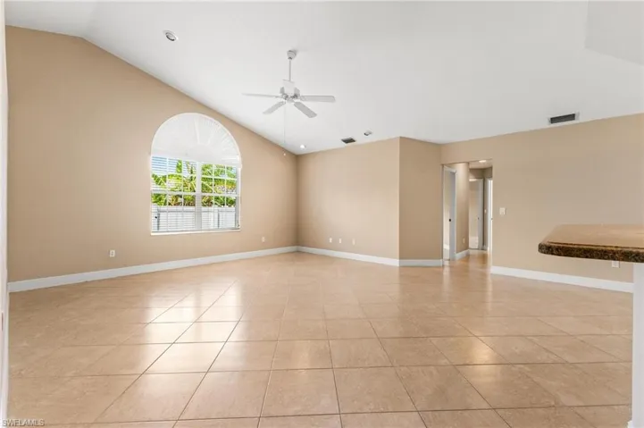 Unfurnished room featuring light tile patterned flooring, a ceiling fan, lofted ceiling, baseboards, and visible vents