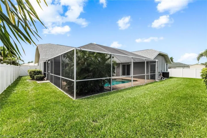 Rear view of house featuring cooling unit, a fenced backyard, a yard, and a lanai
