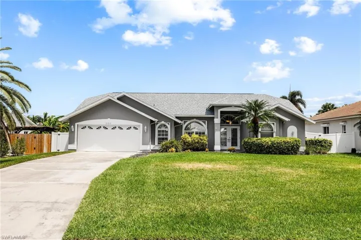 View of front of home with stucco siding, an attached garage, french doors, driveway, and a front lawn