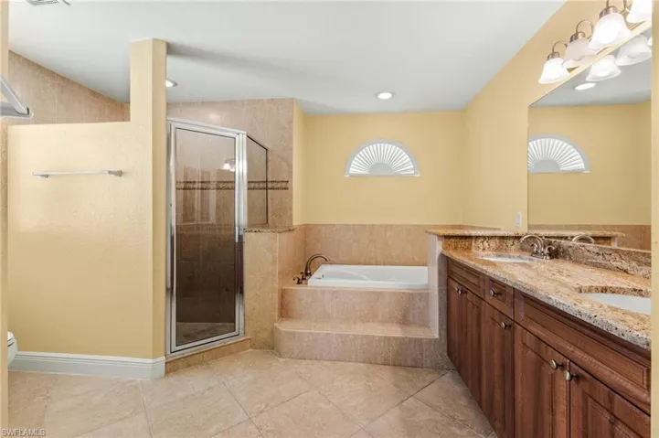 Full bathroom featuring a shower stall, double vanity, a bath, and a sink