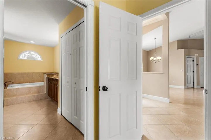 Corridor with baseboards, a notable chandelier, and light tile patterned floors