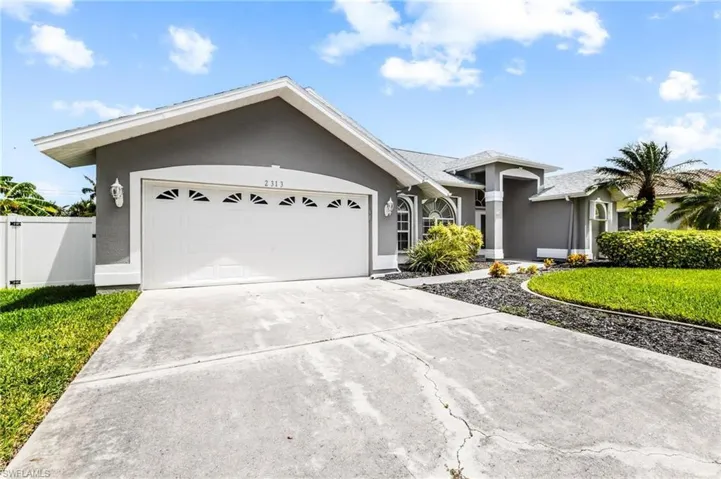 View of front facade featuring concrete driveway, stucco siding, fence, an attached garage, and a front lawn