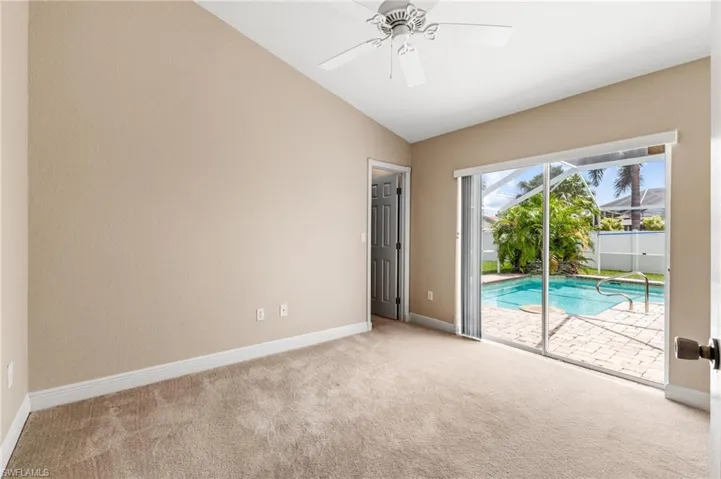 Spare room featuring a ceiling fan, carpet, baseboards, and vaulted ceiling