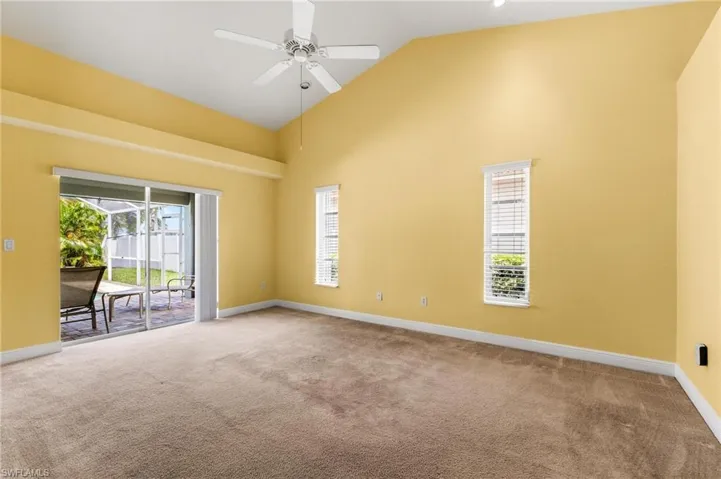 Carpeted spare room featuring high vaulted ceiling, baseboards, ceiling fan, and a wealth of natural light