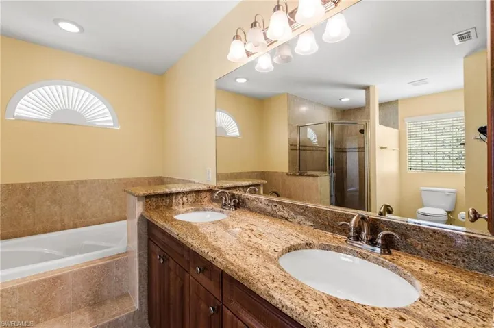 Full bathroom with a shower stall, visible vents, toilet, and a sink