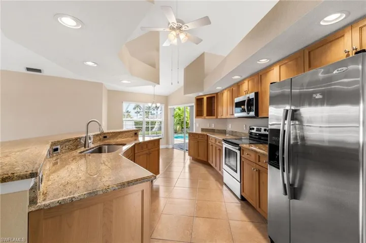 Kitchen featuring light tile patterned flooring, visible vents, appliances with stainless steel finishes, lofted ceiling, and a sink