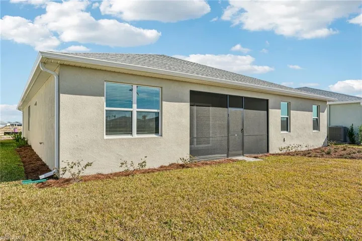 Back of house with central AC unit, a lawn, and a sunroom