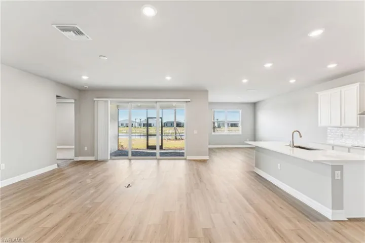 Kitchen featuring sink, decorative backsplash, light hardwood / wood-style flooring, and white cabinets