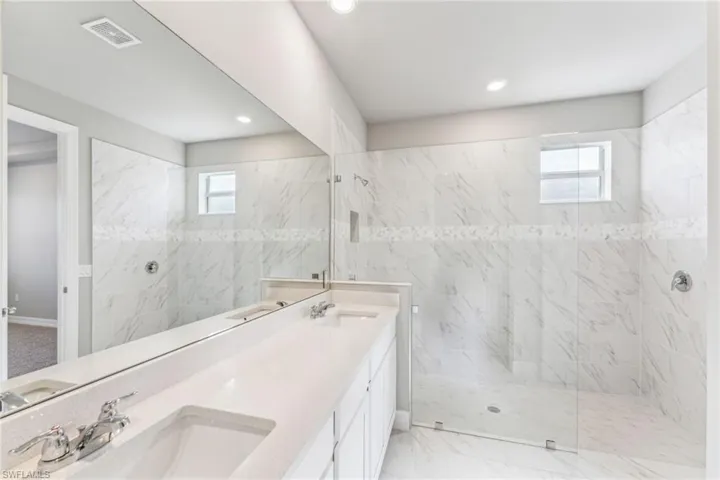 Bathroom with vanity, plenty of natural light, and a tile shower