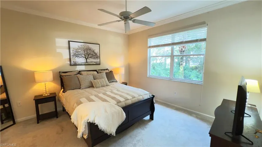 Bedroom with newer light carpet, crown molding, and a ceiling fan