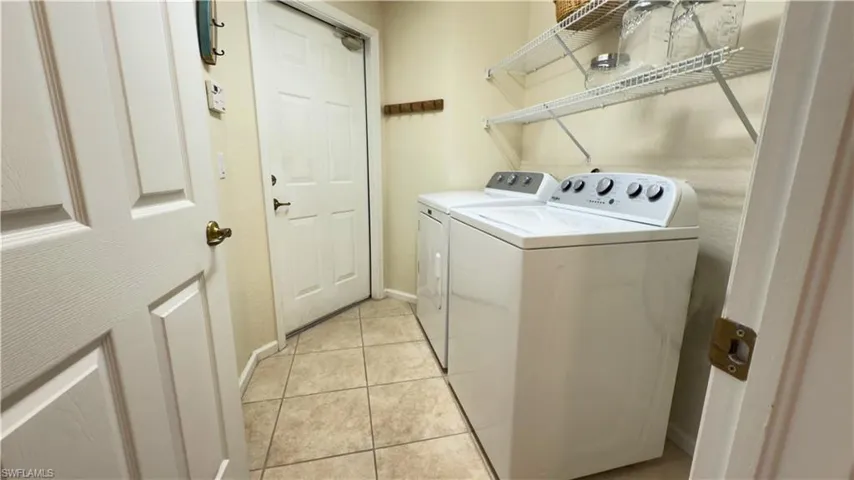Laundry room featuring  washing machine and dryer, laundry area with shelving and light tile patterned floors