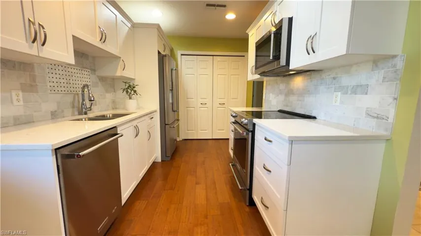 Kitchen with light quartz countertops, stainless steel appliances, dark wood finished floors and  Pantry.
