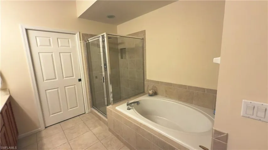 Full bath featuring tile patterned floors, a large bathtub, and a shower stall with upgraded rain shower head