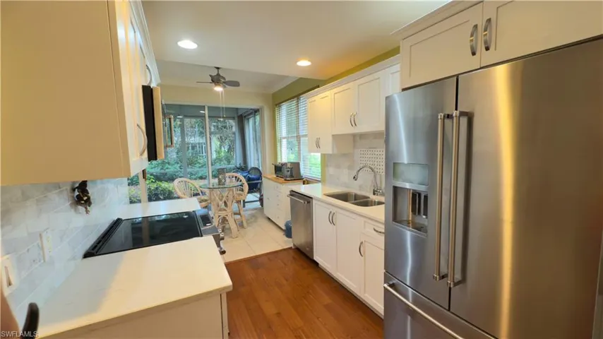 Kitchen featuring light quartz countertops, ceiling fan, stainless steel appliances and glass backsplash