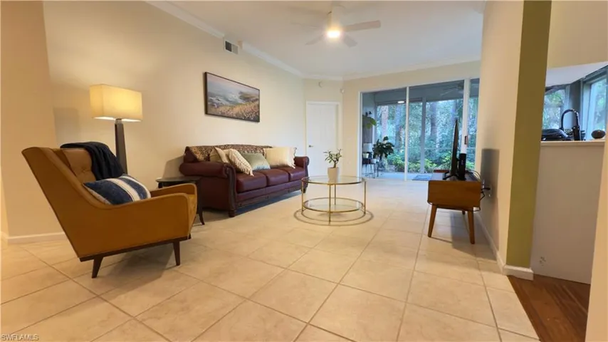 Living room featuring a wealth of natural light, crown molding, and newer ceiling fan with light