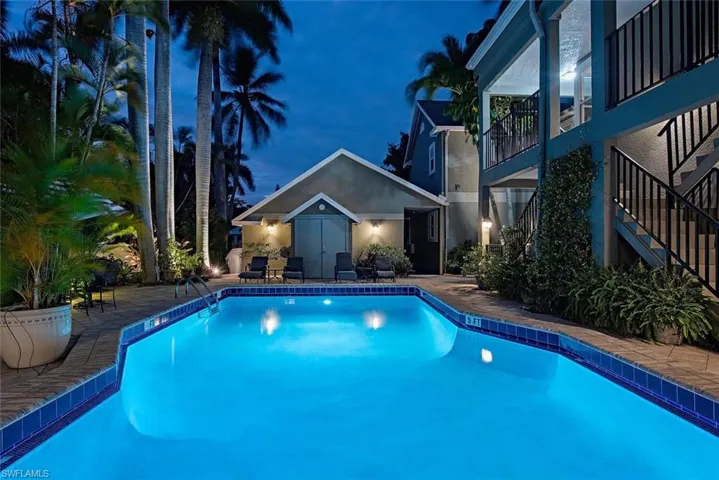 Pool at night featuring an outdoor pool, a patio, and a balcony