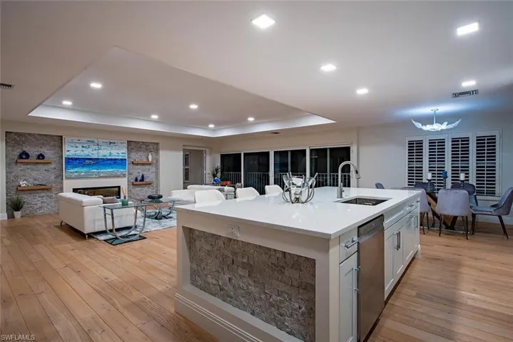 Kitchen featuring light stone countertops, open floor plan, light wood-style floors, white cabinets, and recessed lighting