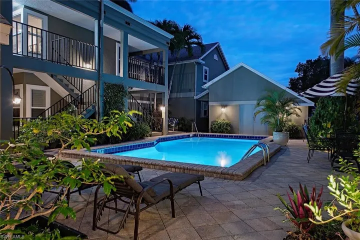 Community pool featuring a patio area, stairs, and a balcony