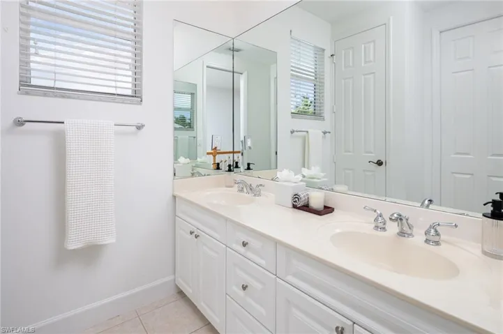 Full bathroom with double vanity and light tile patterned flooring