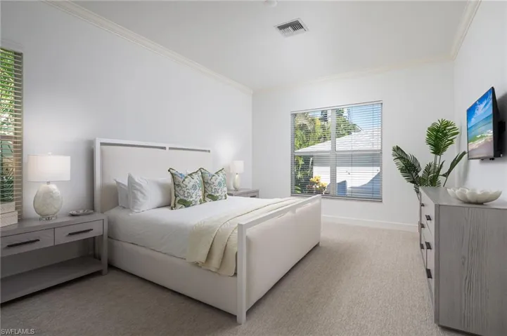 Bedroom featuring ornamental molding, light colored carpet, and multiple windows