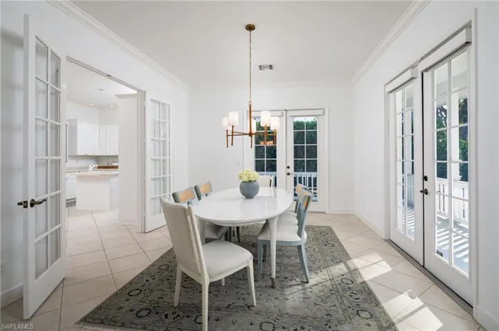 Dining area featuring french doors, ornamental molding, light tile patterned floors, and a chandelier